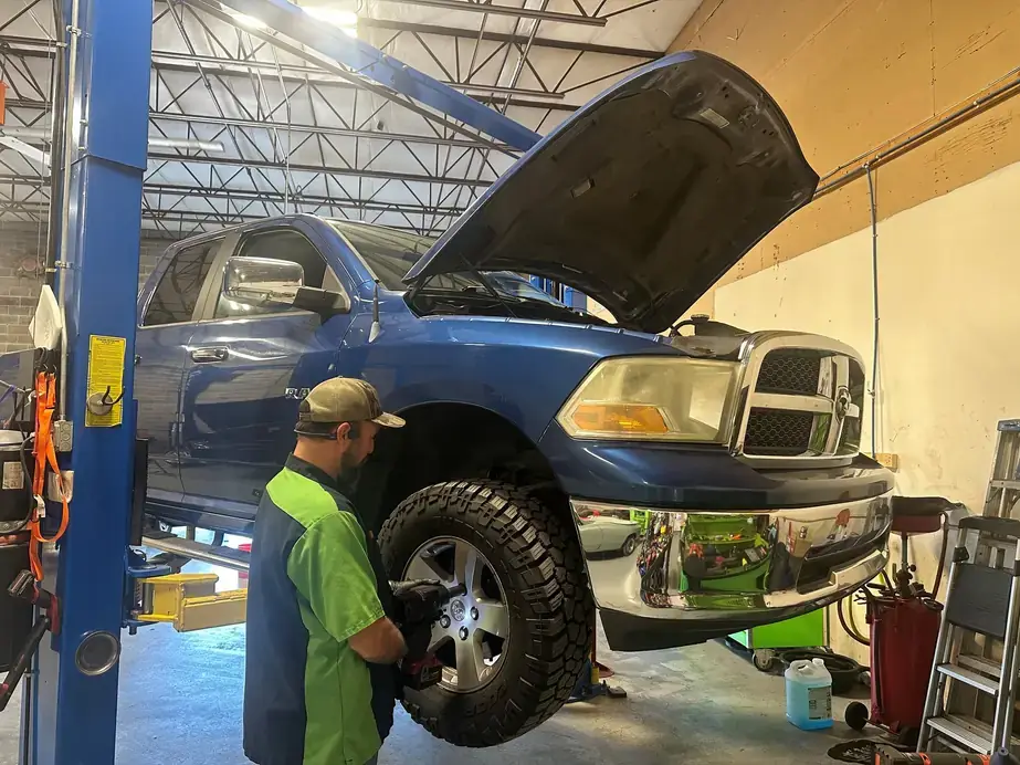 A Lug Nutz Automotive technician servicing a wheel on a blue pickup truck in the shop