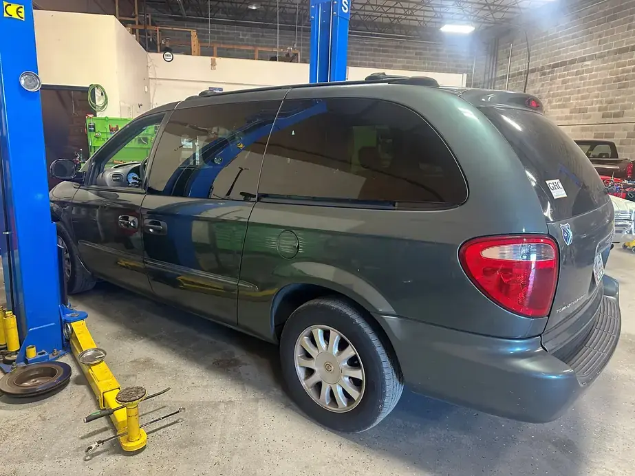 A customer minivan raised on the lift in the Lug Nutz Automotive service bay