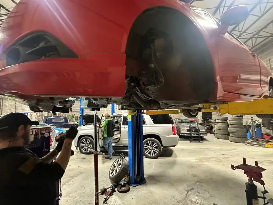 Underside of a red truck raised on the lift at Lug Nutz Automotive during brake work