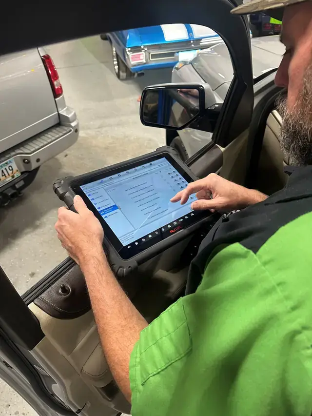 A Lug Nutz Automotive technician running a diagnostic scan tool inside a customer vehicle