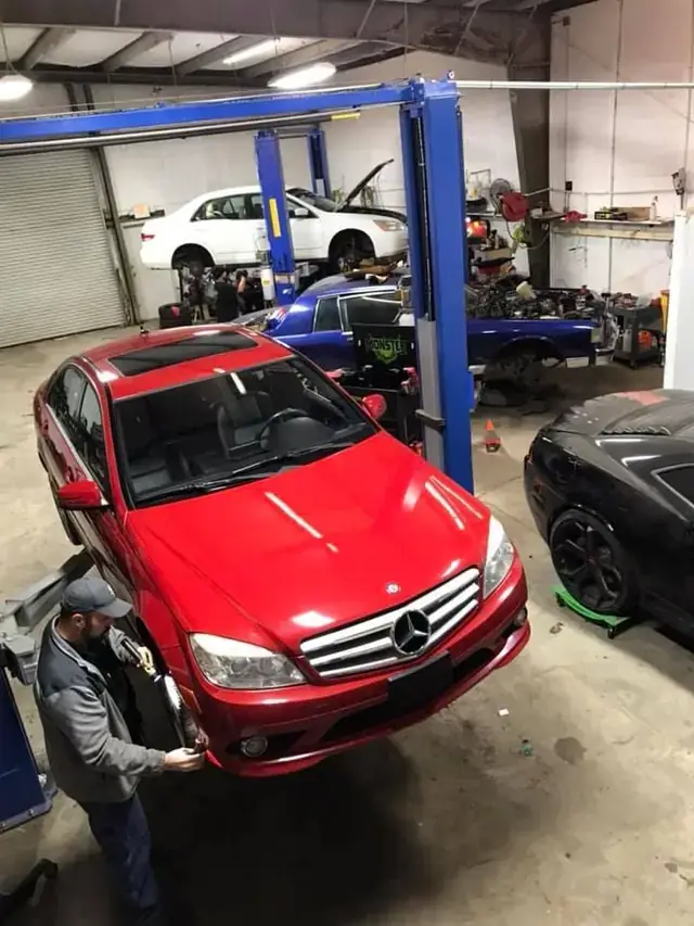 A red Mercedes C-Class on the lift in a wide multi bay shot